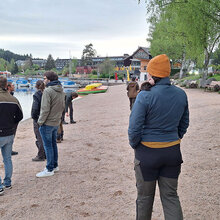 Studierende stehen am Ufer eines Sees