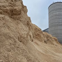 Ein großer Berg Sägespäne vor einem Silo auf dem Werksgelände