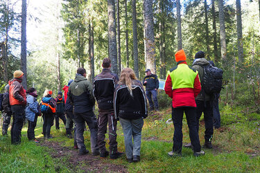 Studierende stehen um einen Referenten im Wald