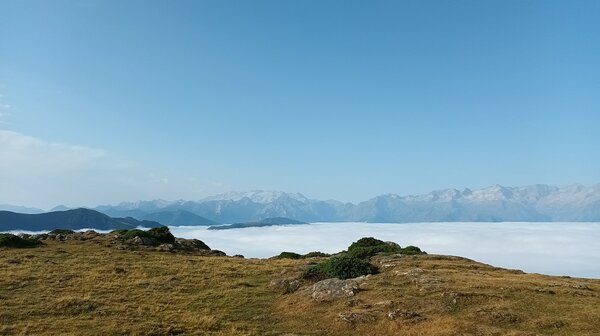 Blick über ein wolkenbehangenes Tal auf eine gegenüberliegende Bergkette