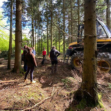 Studierende stehen neben einer Forstmaschine im Wald