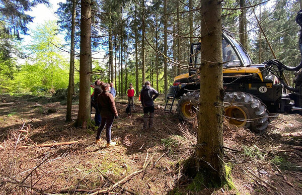 Studierende stehen neben einer Forstmaschine im Wald