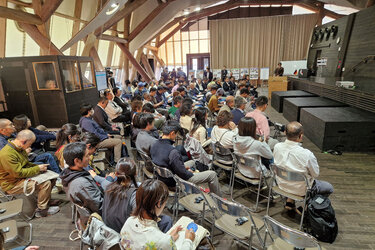 Blick zum Redner seitlich über das Publikum hinweg