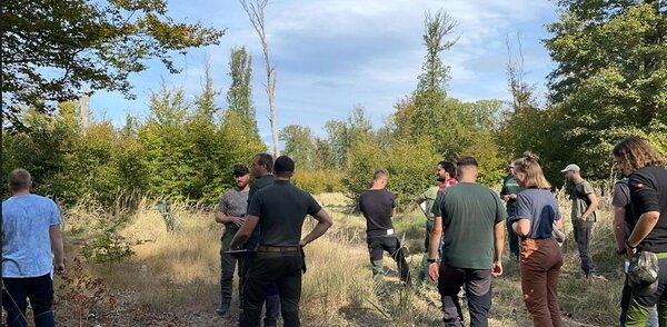 Studierende im Wald lauschen den Referenten