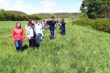 Studierende stehen in einer Wiese bei einer Exkursion