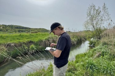 Ein Student steht am Ufer und macht Notizen
