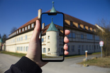 Blick auf das Hauptgebäude der Hochschule Rottenburg durch eine Smartphone-Kamera