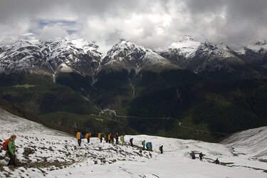 Studierende wandern in den Alpen im Schnee. Im Hintergrund stehen verschneite Berggipfel.