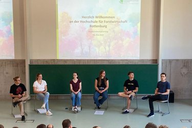 6 Studierende sitzen auf der Bühne und stellen ihren Stdueingang vor