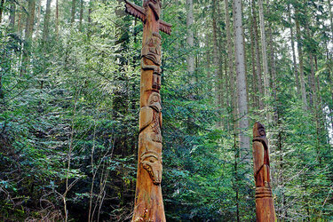 Zwei Holzskulpturen stehen an einem Waldweg