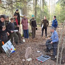 Studierende stehen um ein Bodenprofil im Wald