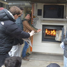 Studierende wärmen sich an einem offenen Ofen