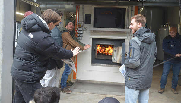 Studierende wärmen sich an einem offenen Ofen