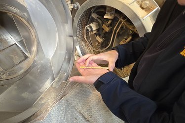 Ein Mitarbeiter zeigt ein Pellet auf der Handinnenfläche liegend