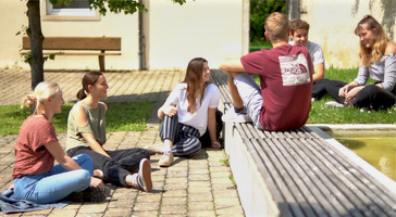 Eine Gruppe Studierende sitzt im Innenhof der Hochschule Rottenburg im Kreis und unterhält sich