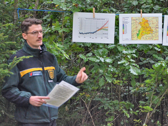 Herr Axel Miske steht im Wald und referiert.